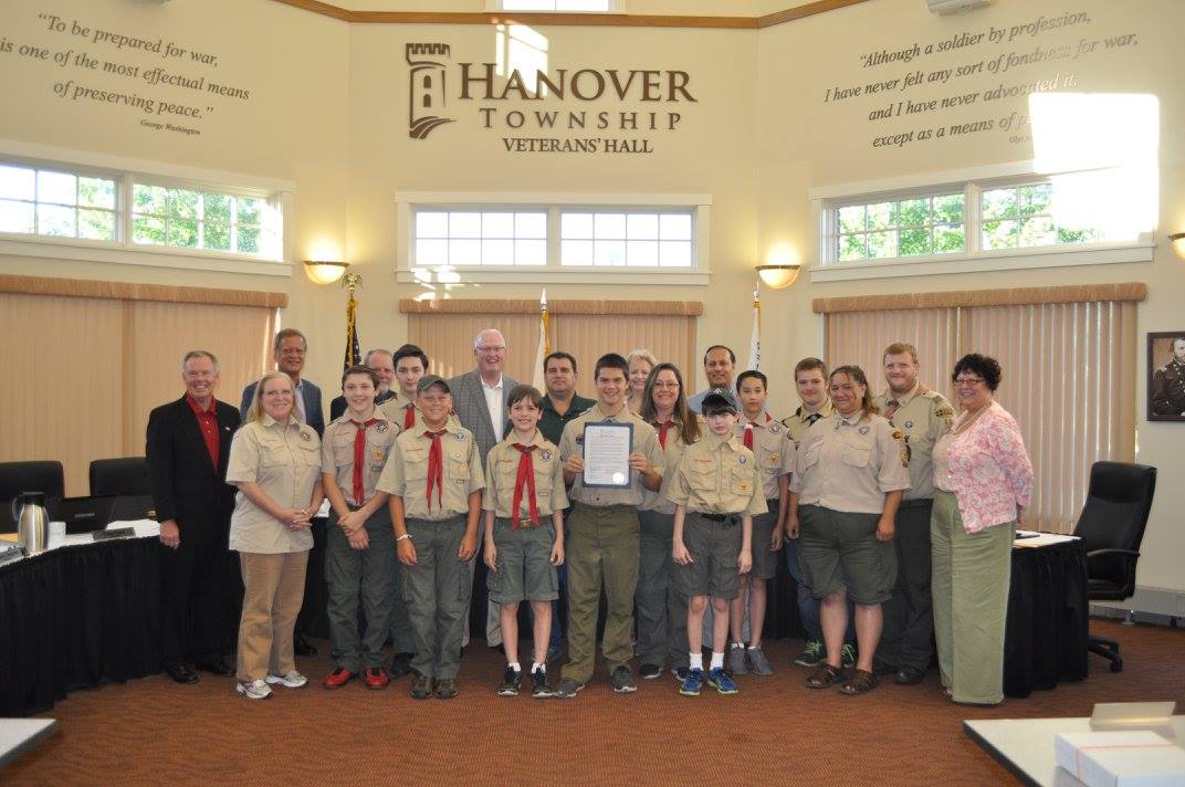 Men and women smile and stand with a group of boy scouts.