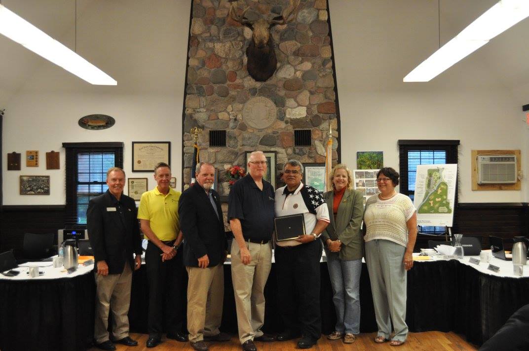 Five men and two women smile together at a board meeting.