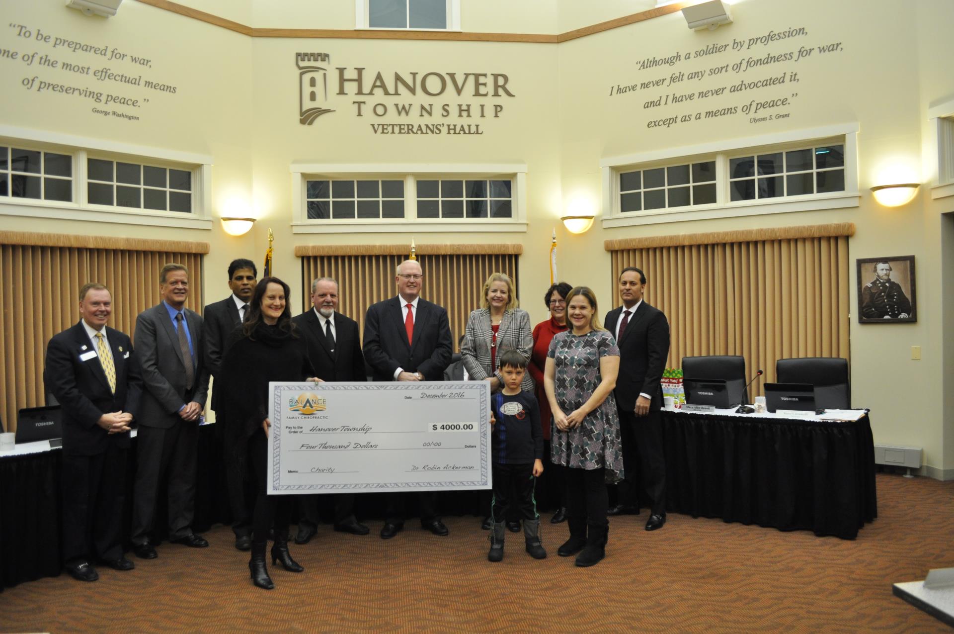 Six men, four women, and one boy stand around a giant check for 4,000 dollars.