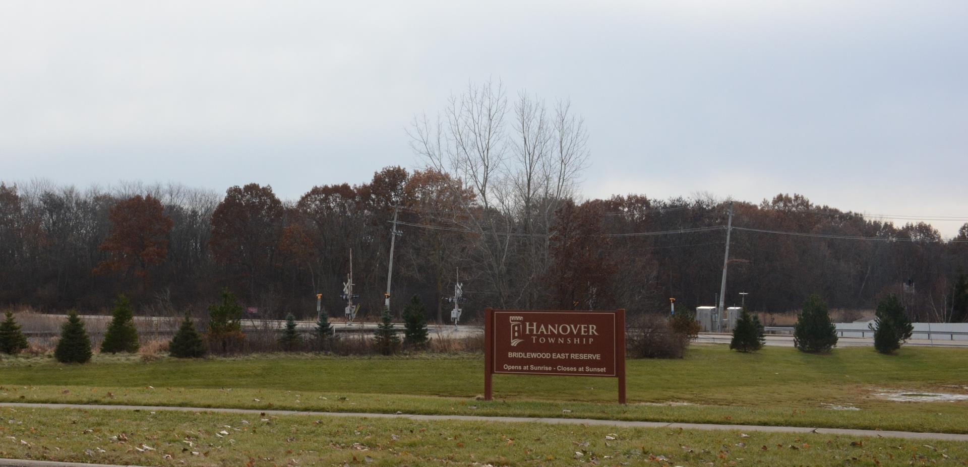 Maroon Hanover Township Bridlewood East Reserve sign displayed in front of trees on a cloudy day. 