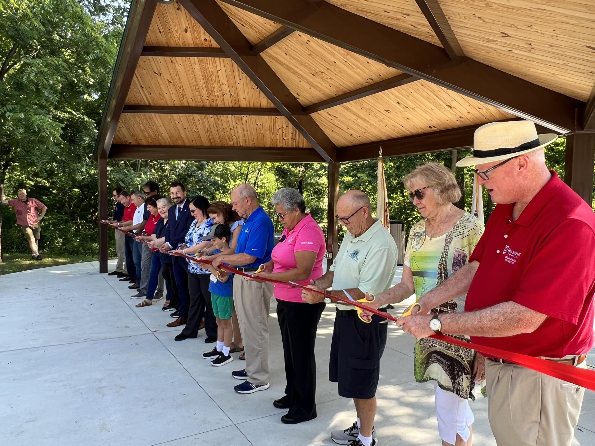 Township and local officials and leaders standing behind a red ribbon to cut